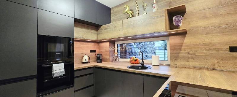 Küche in einem Einfamilienhaus mit dunklen Schränken und einem Boden in Holzoptik.