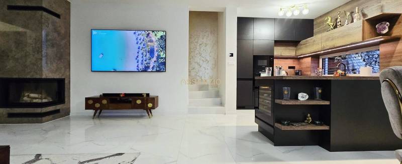 Wohnzimmer in einem Einfamilienhaus mit Kamin und Kücheninsel, Boden mit Holzdekor.