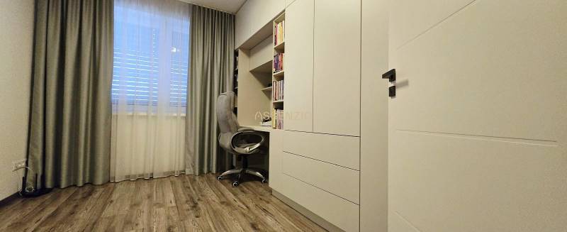 Arbeitszimmer in einem Einfamilienhaus mit Arbeitsecke, weißen Möbeln und Holzboden.