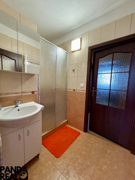 Badezimmer mit Dusche und Waschbecken in einer 3-Zimmer-Wohnung, Fliesen und Spiegel.