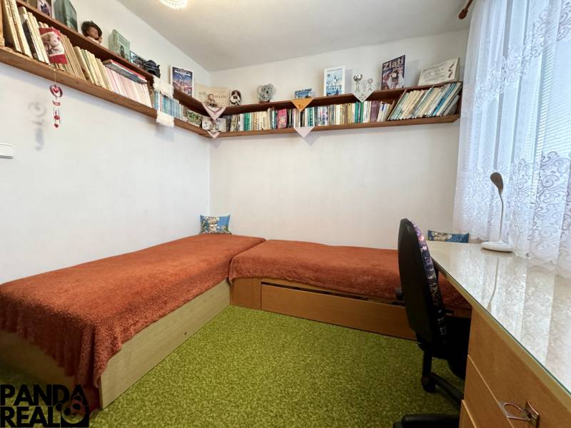Ein Zimmer in einer 3-Zimmer-Wohnung mit Regalen voller Bücher und einem einfachen Schreibtisch.