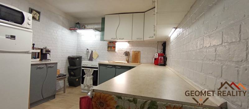 Küche in einem Einfamilienhaus mit weißen Ziegelwänden und Küchengeräten.