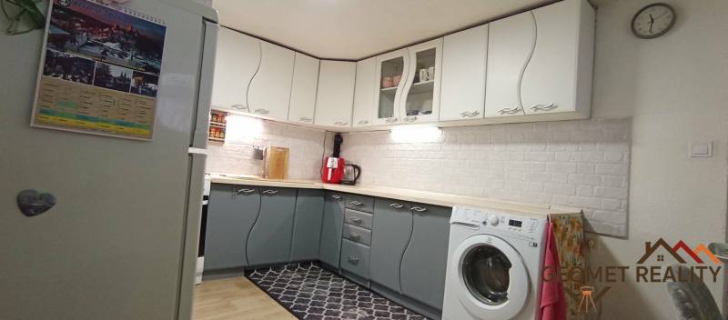 Küche in einem Einfamilienhaus mit weißen und grauen Schränken, Boden mit Holzdekor.