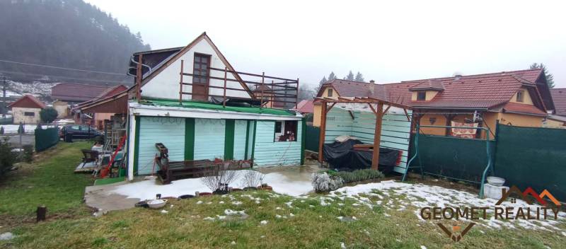 Einfamilienhaus in der Cintorínska-Straße in Divín mit einem Unterstand im Hof und schneebedecktem Rasen.