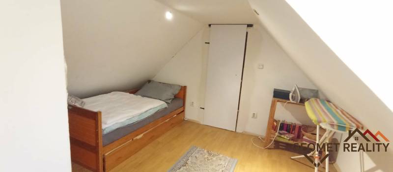 Dachzimmer mit Dachschräge, Bett und Boden in Holzoptik in einem Einfamilienhaus.