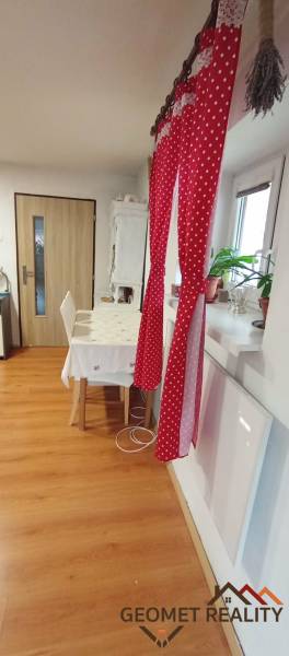 Esszimmer in einem Einfamilienhaus mit rotem Vorhang, Tisch und Boden in Holzoptik.