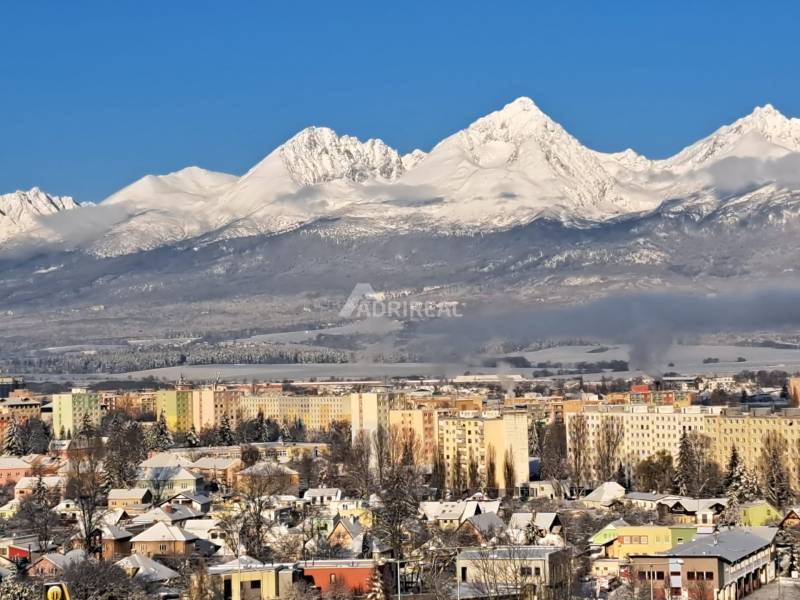 Verschneite Berge mit Blick auf einen Teil der Stadt Poprad und mehrstöckige Gebäude.