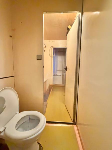 Badezimmer mit Toilette in einer 3-Zimmer-Wohnung, beige Wände, gelber Boden.