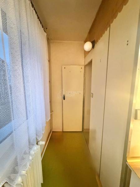 Ein enger Flur in einer 3-Zimmer-Wohnung mit Bodenbelag und weißen Türen.