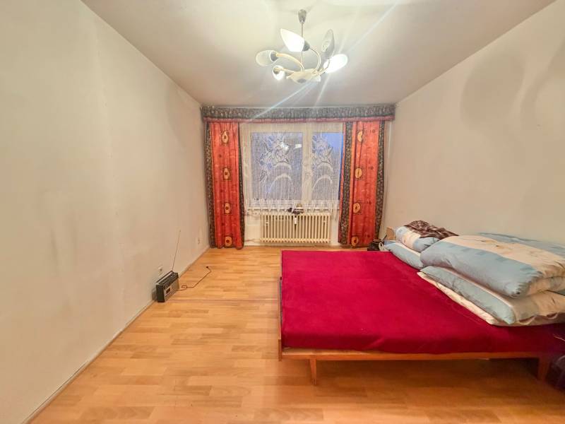 Schlafzimmer in einer 3-Zimmer-Wohnung mit Bett, Holzboden und Licht.