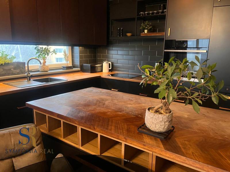 Küche in einer 2-Zimmer-Wohnung mit Holzboden und schwarzer Küchenzeile.