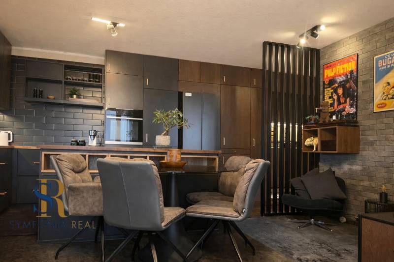 Küche in einer 2-Zimmer-Wohnung mit dunklen Schränken und dekorativen Postern an der Wand.