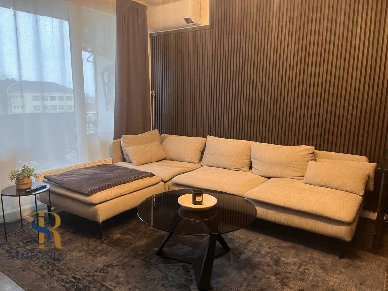 Helles Sofa in einer 2-Zimmer-Wohnung mit Holzwanddekor und Tisch.