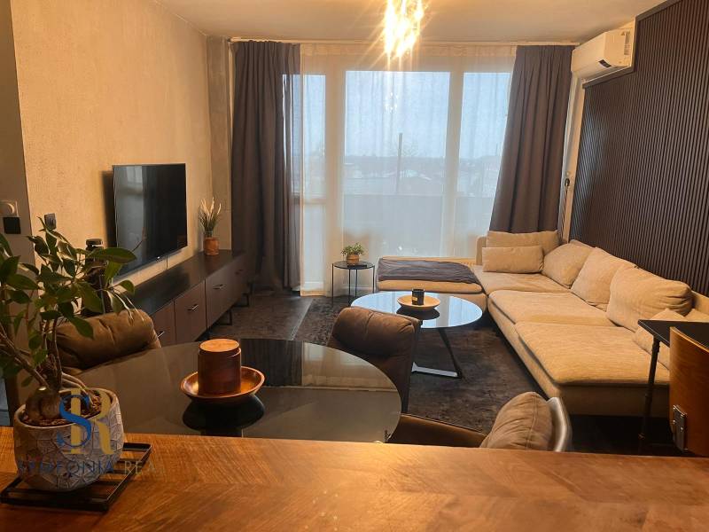 Wohnzimmer mit Holzdekorboden, Sofa und Fernseher in einer Zweizimmerwohnung.