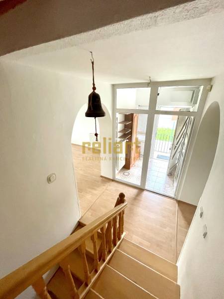 Treppe mit Holzboden, Eingangstür und Türklingel in einem Einfamilienhaus.