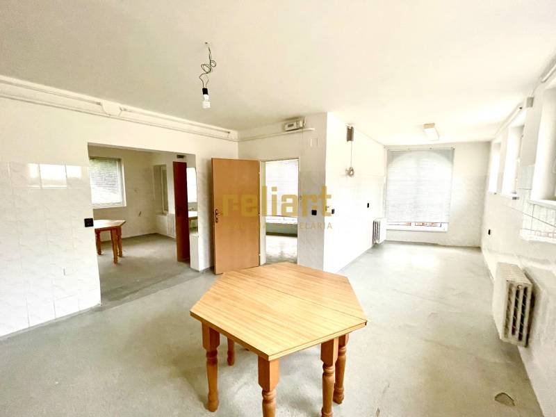 Ein geräumiges Zimmer mit Holztischen und Heizkörpern in einem Einfamilienhaus.