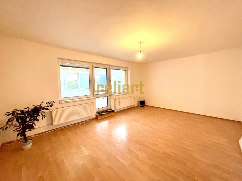 Ein Zimmer in einem Einfamilienhaus mit einem Boden in Holzoptik und großen Fenstern.