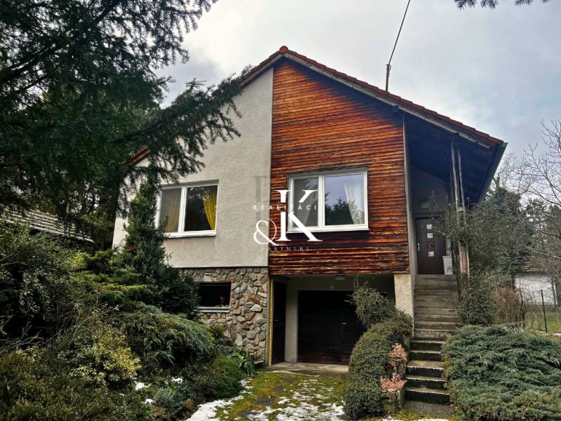 Ein Ferienhaus in Modra mit Holzverkleidung und Garage, umgeben von Grün.