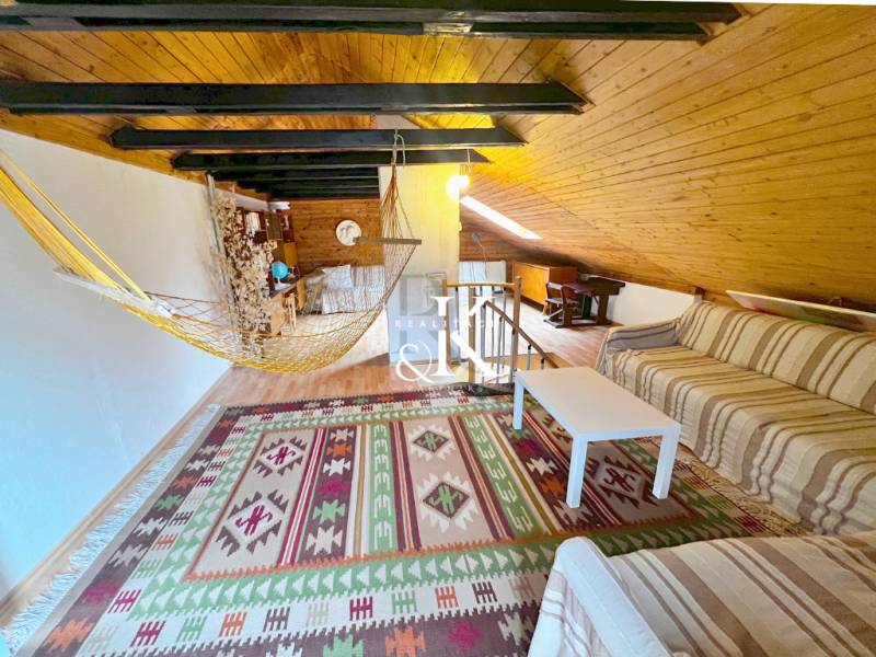 Dachboden der Hütte mit Sofa, Hängematte und Boden in Holzoptik.