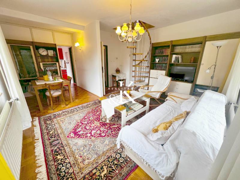 Das Innere der Hütte mit einer Wendeltreppe, einem Fernseher und einem Tisch auf einem Boden mit Holzdekor.