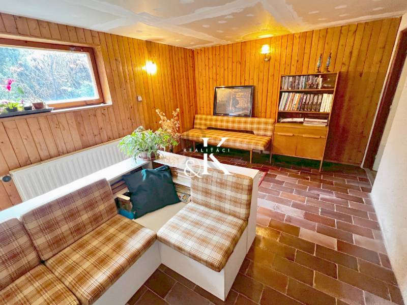 Innenraum der Hütte mit Wohnzimmer, rustikalen Möbeln und Ziegelboden.