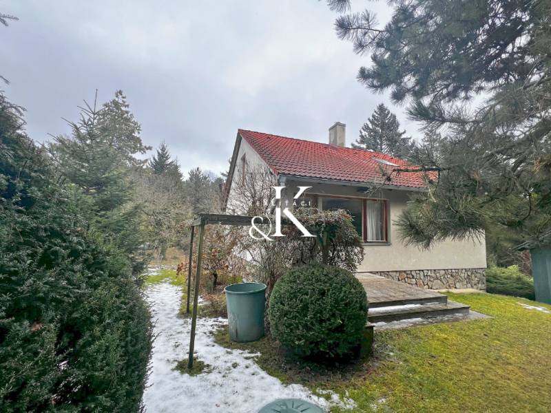 Gartenhütte in Modra, umgeben von Grün und einer Schneedecke auf dem Gehweg.