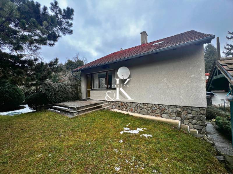 Hütte bei Modra mit einer Rasenfläche, Steintreppen und Nadelbäumen.