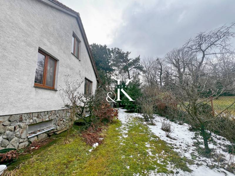 Garten bei der Hütte in Modra mit Rasen, Schnee und Gehölzen entlang des Hauses.