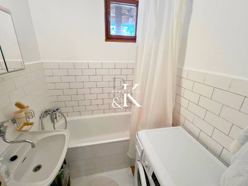 Badezimmer in der Hütte mit Badewanne, Waschmaschine und weißen Fliesen.