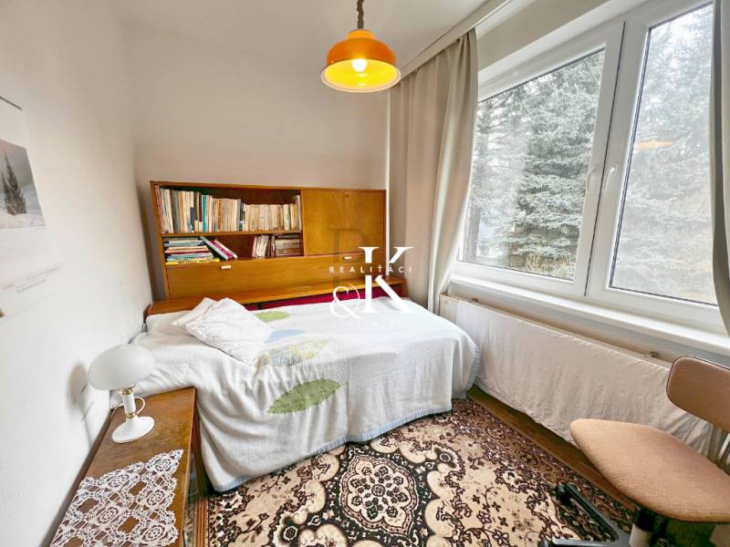 Izba in einer Hütte mit einem Bücherregal, einem Bett und einem großen Fenster.