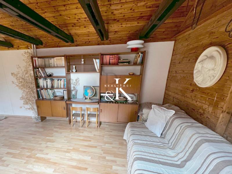 Innenraum einer Hütte mit Holzbalken, Möbeln und einem Boden mit Holzdekor.