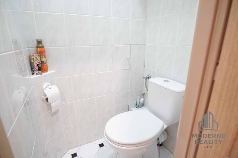 Toilette mit Keramikfliesen, Toilettenpapierhalter, dekorative Accessoires, 4-Zimmer-Wohnung.