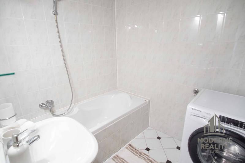 Badezimmer mit Duschwanne, Waschbecken und Waschmaschine in einer 4-Zimmer-Wohnung.