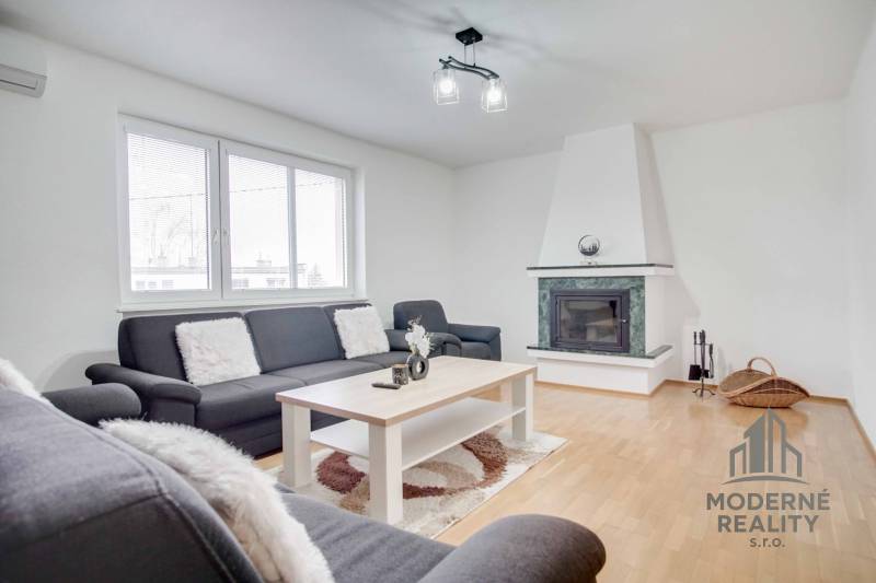 Wohnzimmer in einer 4-Zimmer-Wohnung mit Kamin und Boden in Holzoptik.