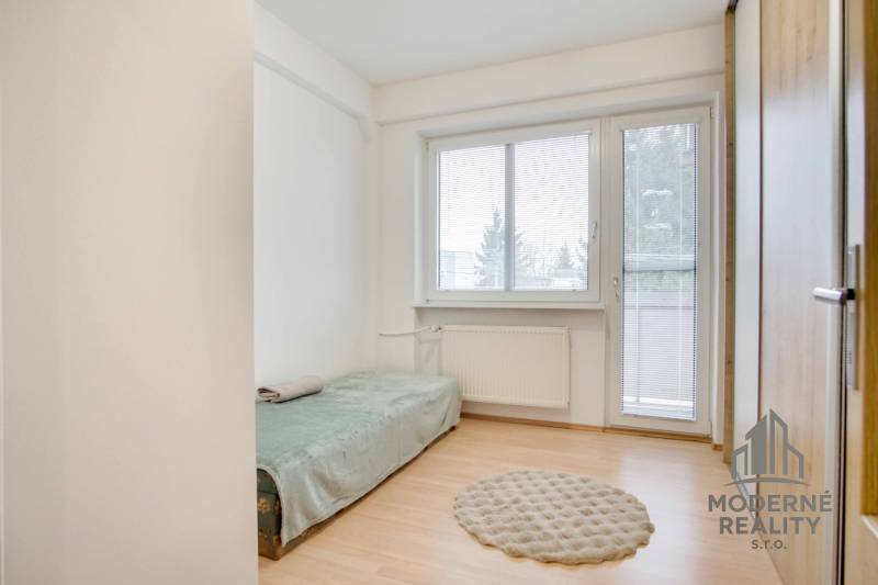 Einfaches Zimmer mit Holzboden und einem ausziehbaren Bett in einer 4-Zimmer-Wohnung.