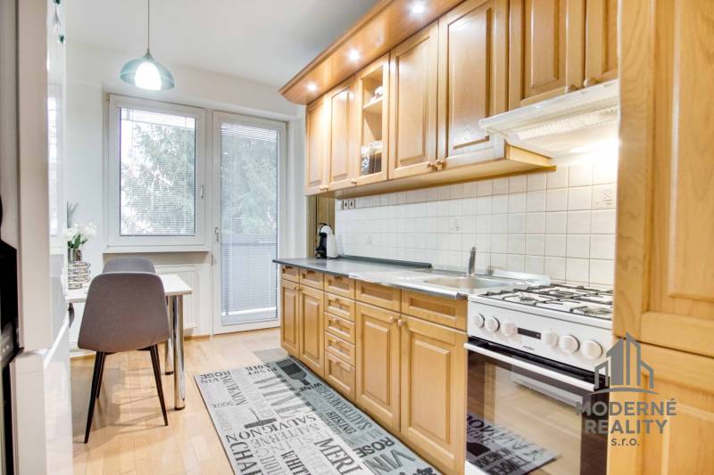 Küche in einer 4-Zimmer-Wohnung mit Holzboden und Esstisch.