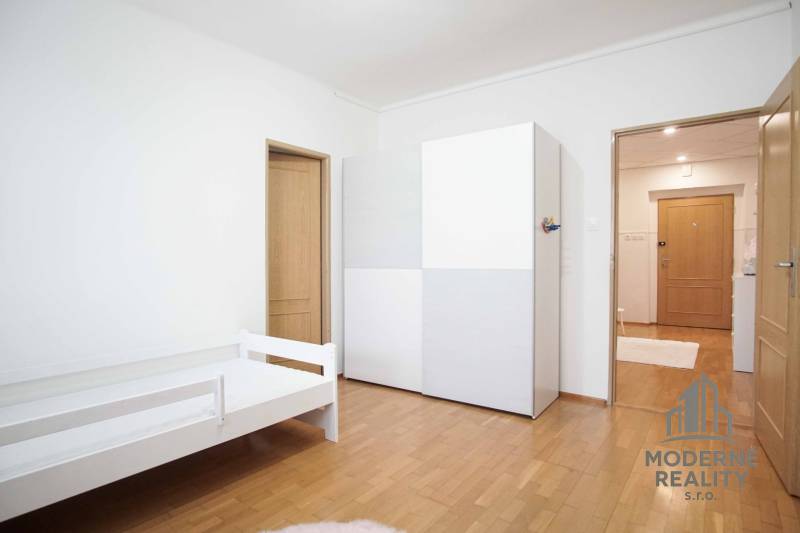 Helles Zimmer mit Bett, Schrank und Boden in Holzoptik in einer 4-Zimmer-Wohnung.