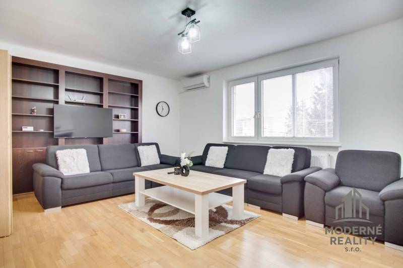 Wohnzimmer in einer 4-Zimmer-Wohnung mit Sofa, Couchtisch und Boden in Holzoptik.