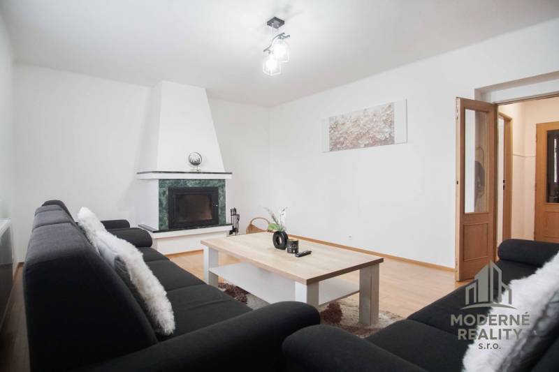 Wohnzimmer in einer 4-Zimmer-Wohnung mit Kamin und Boden in Holzoptik.