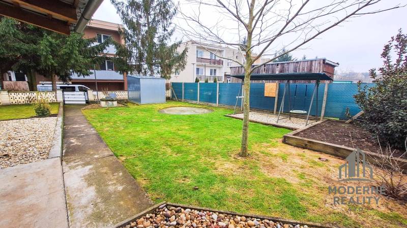 Garten bei einer 4-Zimmer-Wohnung in Kolta, mit Grünflächen, Gehweg und Schaukel.