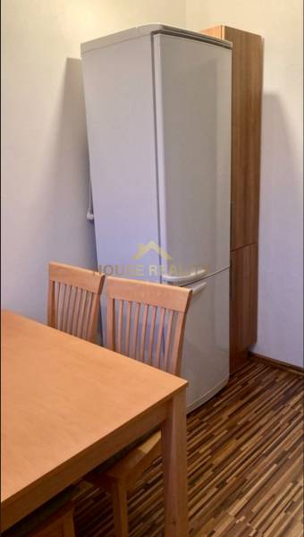 Küche in einer 3-Zimmer-Wohnung mit Kühlschrank, Holztisch und Stühlen, Boden mit Holzdekor.