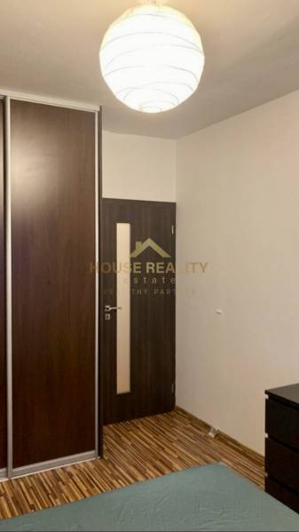 Ein Interieur mit einem dunklen Einbauschrank, Türen und einem Boden mit Holzdekor in einer 3-Zimmer-Wohnung.