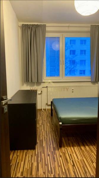 Schlafzimmer in einer 3-Zimmer-Wohnung mit Bett, Kommode und Bodenbelag in Holzoptik.