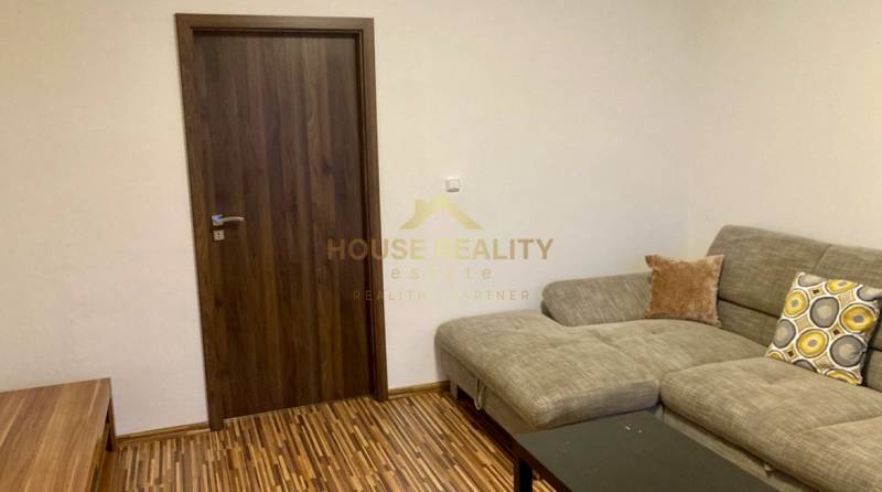 Wohnzimmer mit Sofa, Holzboden und dunklen Türen in einer 3-Zimmer-Wohnung.