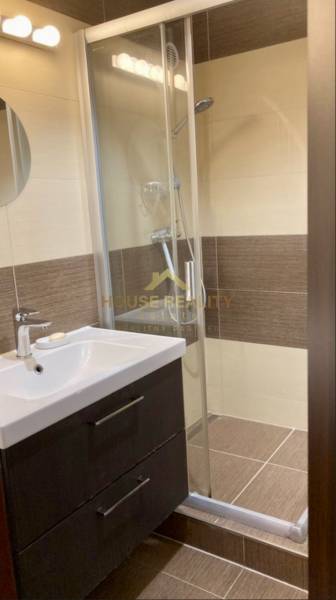 Badezimmer mit Waschbecken, Duschkabine und braunen Wandfliesen in einer 3-Zimmer-Wohnung.