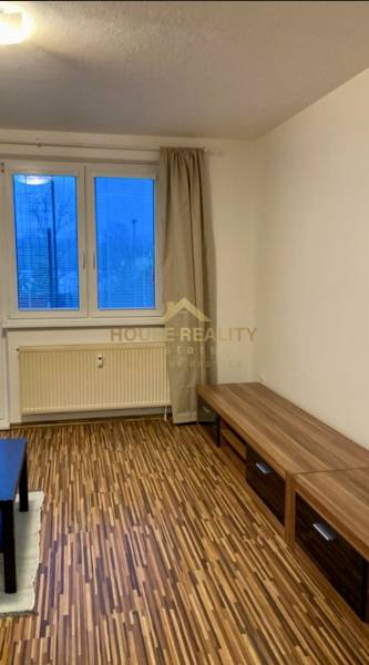 Wohnzimmer in einer 3-Zimmer-Wohnung mit Holzboden und Blick durch ein großes Fenster.