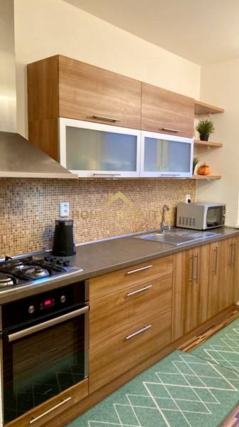 Küche mit Holzdekor und eingebauten Geräten in einer 3-Zimmer-Wohnung.