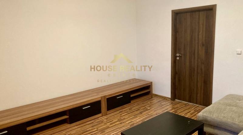 Wohnzimmer mit Holzboden in einer 3-Zimmer-Wohnung, helle Wände, Holzmöbel.