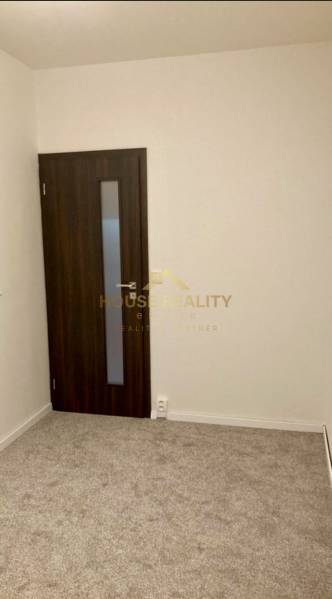 Ein Zimmer in einer 3-Zimmer-Wohnung mit Teppichboden und dunklen Türen.