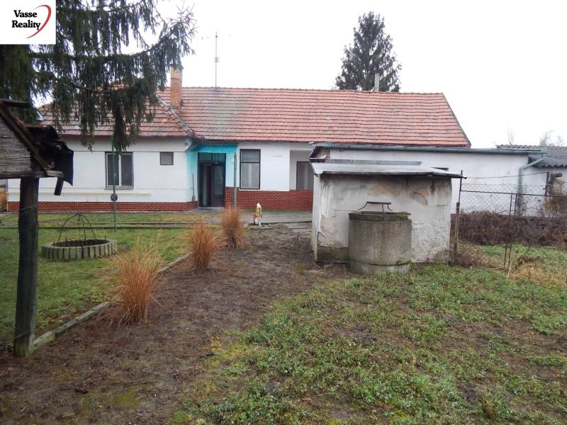 Ein Einfamilienhaus in Kravany nad Dunajom mit einem Rasen im Garten und einem Brunnen auf dem Grundstück.